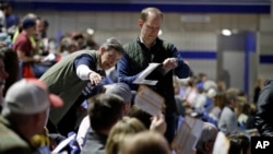 Precinct 68 Iowa Caucus voters seated in the Biden section hold up their first votes as they of the caucus as they are counted at the Knapp Center on the Drake University campus in Des Moines, Iowa, Monday, Feb. 3, 2020. (AP Photo/Gene J. Puskar)
