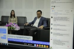 Facebook users comment during a VOD Roundtable show on judicial corruption in Cambodia with host Lim Thida, left, and one of her guests, Justice Ministry spokesman Chin Malin, VOD's studio, in Phnom Penh, Sept. 11, 2019. (Tum Malis/VOA Khmer)