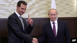 FILE - Russian President Vladimir Putin, right, shakes hands with Syrian President Bashar Assad in the Black Sea resort of Sochi, Russia, Nov. 20, 2017.