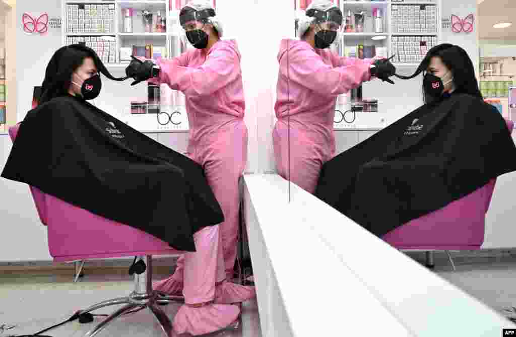 A stylist and a customer wear protective equipment as a preventive measure against the COVID-19 coronavirus, at a beauty salon in Bogota, June 23, 2020.
