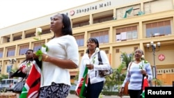 Survivors and relatives of victims carry Kenyan national flags as they attend the first anniversary memorial service of the Westgate shopping mall terrorist attack in Kenya's capital Nairobi, Sept. 21, 2014. 