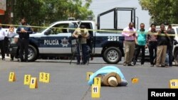 Evidence identifiers are placed next to the body of journalist Javier Valdez at a crime scene in Culiacan, Mexico, May 15, 2017.