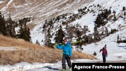 Glenn Cain (L) of Alma, Colorado and Mary Taylor of Silverthorne, Colorado walk on exposed pavement after backcountry skiing in Summit County, Colorado on Dec. 3, 2021. 