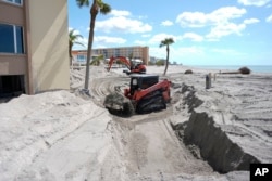 Scott Bennett, a contractor who specializes successful  tempest  recovery, uses a skid steer to region   soil  astir   1.5 meters heavy  from the patio of a beachfront condominium successful  Venice, Fla., pursuing  the transition  of Hurricane Milton, Oct. 12, 2024.