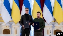 乌克兰总统府新闻处公布的照片显示乌克兰总统泽连斯基与芬兰总统斯图布手持两人签署的双边协议。(2024年4月3日)