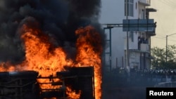 Mobil dibakar di hadapan polisi anti-huru-hara dalam demonstrasi yang dilakukan Ayotzinapa Teacher Training College di Chilpancingo, Meksiko (13/10). 