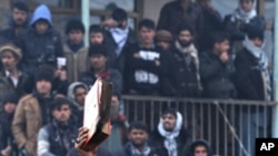 An Afghan demonstrator holds a copy of a half-burnt Quran, allegedly set on fire by US soldiers, at the gate of Bagram airbase during a protest against Koran desecration at Bagram, about 60 kilometers (40 miles) north of Kabul, February 21, 2012.