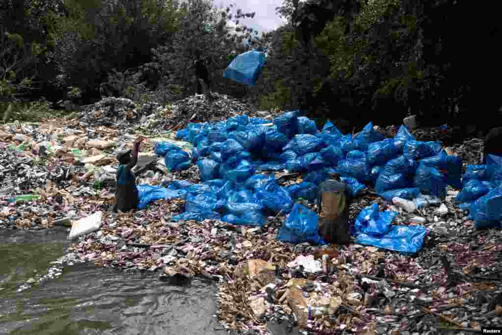 A worker from Hennops River Revival, an environmental NGO, throws a bag filled with rubbish during a clean-up of an island formed from mostly polystyrene and plastic waste in the Hennops River, Centurion, South Africa.