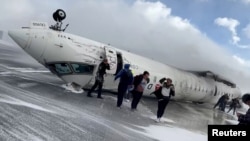 FILE - Passengers leave a Delta Air Lines CRJ-900 jet after it crashed on landing at Toronto Pearson International Airport in Mississauga, Ontario, Canada Feb. 17, 2025 in a still image from video. 