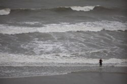 Dark clouds and high surf produced by Tropical Storm Isaias can be seen as a man continues to fish on the beach in North Myrtle Beach, S.C., Aug. 3, 2020.