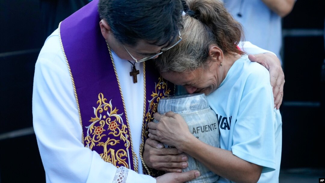 Filipino Catholic priest Flavie Villanueva, left, consoles Melinda Lafuente as she holds the urn containing the remains of her son Angelo, during an interment ceremony for victims of extrajudicial killings, in Caloocan City, Philippines, March 12, 2025.