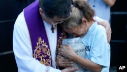 Filipino Catholic priest Flavie Villanueva, left, consoles Melinda Lafuente as she holds the urn containing the remains of her son Angelo, during an interment ceremony for victims of extrajudicial killings, in Caloocan City, Philippines, March 12, 2025.