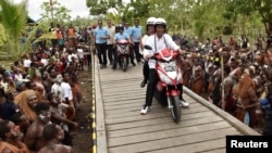 Presiden Joko Widodo dan Ibu Negara Iriana mengendarai sepeda motor listrik dalam kunjungan ke Agats, di Asmat, Provinsi Papua, 12 April 2018. (Antara Foto/Puspa Perwitasari/via REUTERS) 