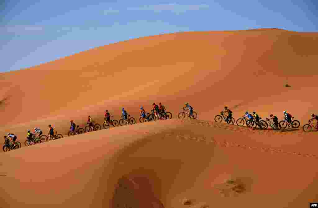 Competitors ride their bikes along sand dunes during the Stage 1 of the 14th edition of Titan Desert 2019 mountain biking race around Merzouga in Morocco.