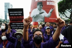 Para mahasiswa menggelar aksi "Indonesia Gelap" sambil memegang plakat bergambar Presiden Indonesia Prabowo Subianto dan anggota kabinetnya, menentang kebijakan efisiensi anggaran baru-baru ini, di dekat istana presiden di Jakarta, 20 Februari 2025. (Willy Kurniawan/REUTERS)