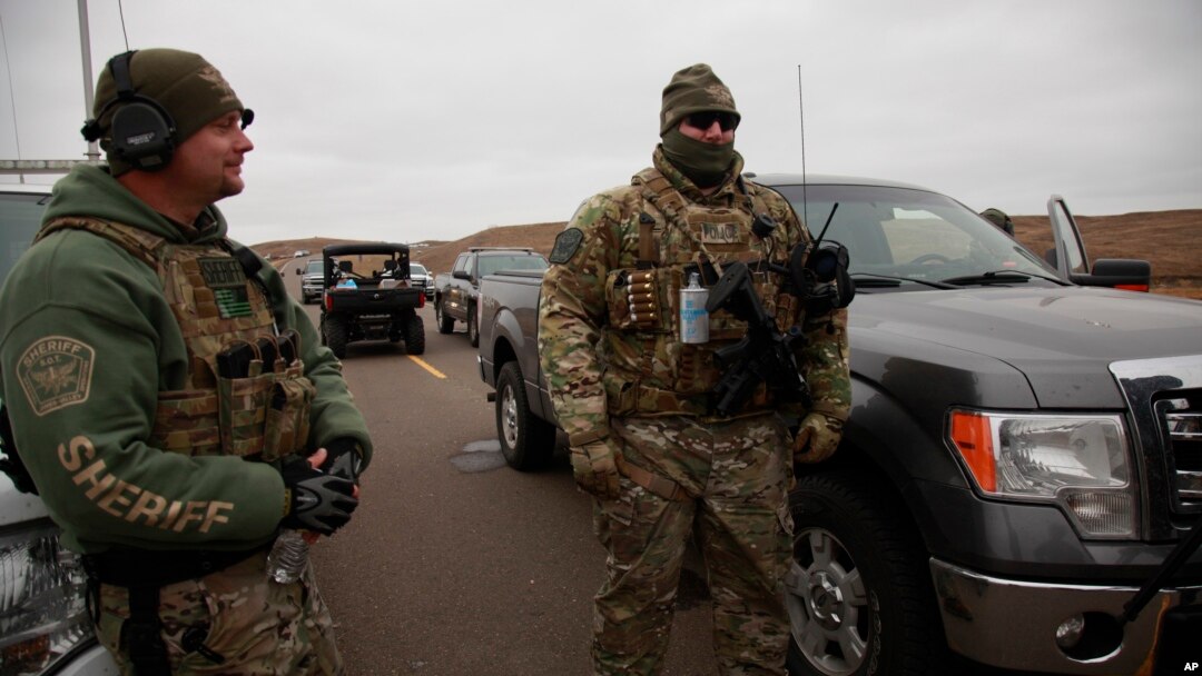 Two members of a local SWAT team talk as they watch protesters demonstrating against the Dakota Access Pipeline encroaching a water source near the Stand Rock Sioux Reservation, in Cannon Ball, North Dakota, Oct. 30, 2016.