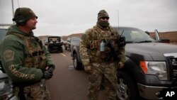 Two members of a local SWAT team talk as they watch protesters demonstrating against the Dakota Access Pipeline encroaching a water source near the Stand Rock Sioux Reservation, in Cannon Ball, North Dakota, Oct. 30, 2016.