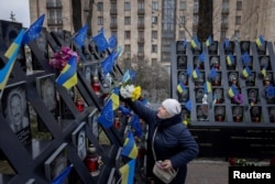 A woman lays flowers at the monument to the "Heavenly Hundred," the people killed during the Ukrainian pro-European Union mass demonstrations in 2014, during an event marking the 10th anniversary of the start of the uprising, in Kyiv, on Nov. 21, 2023.
