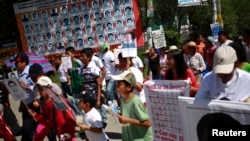 Demonstrators pass by a banner with pictures of the 43 missing students of the Ayotzinapa teacher training college in Tixtla, on the outskirts of Chilpancingo, in the Mexican state of Guerrero, Nov. 13, 2014. 