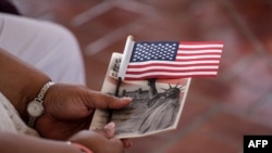 Una mujer sostiene una bandera estadounidense antes de convertirse en ciudadana durante una ceremonia especial de naturalización en honor al Día de la Ciudadanía y al Día de la Constitución, en la Isla Ellis en Nueva York el 16 de septiembre de 2016.
