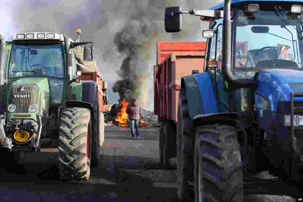 Para petani menutupi jalan RN12 dekat Guingamp, Perancis barat sebagai bagian dari unjukrasa terhadap pemerintah. Para petani menginginkan lebih banyak bantuan, dan mereka mengatakan tidak bisa membayar semua kebutuhan mereka karena harga-harga mandek atau jatuh karena menghadapi pengeluaran yang lebih besar daripada pesaing mereka di negara-negara lain di Uni Eropa.