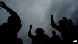 FILE - People raise up their arms during the dedication of a prayer wall outside of the historic Vernon African Methodist Episcopal Church in the Greenwood neighborhood during the centennial of the Tulsa Race Massacre, May 31, 2021, in Tulsa, Oklahoma 