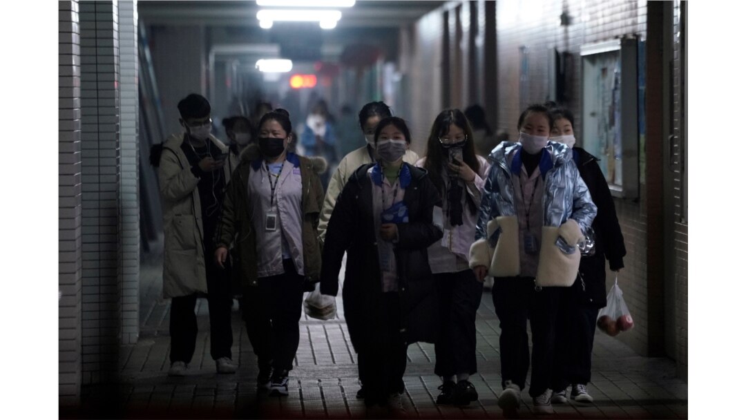Workers wearing masks walk outside their dormitory, in an electronics manufacturing factory in Shanghai, China, as the country copes with an outbreak of a new coronavirus, Feb. 12, 2020.