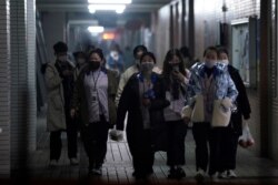 Workers wearing masks walk outside their dormitory, in an electronics manufacturing factory in Shanghai, China, as the country copes with an outbreak of a new coronavirus, Feb. 12, 2020.