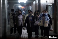 Workers wearing masks walk outside their dormitory, in an electronics manufacturing factory in Shanghai, China, as the country copes with an outbreak of a new coronavirus, Feb. 12, 2020.