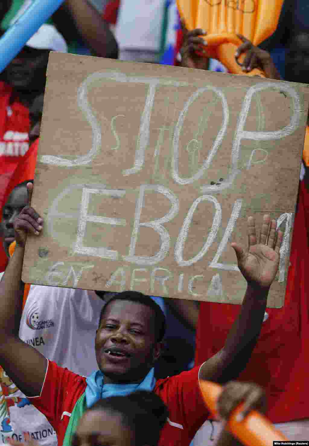 Seorang penonton mengangkat papan bertuliskan pesan anti Ebola saat menunggu pertandingan pembuka Piala Afrika 2015 di Bata (17/1).