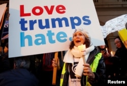 A woman holds a sign and a candle as she takes part in the women's rights event "Lights for Rights", a protest against the inauguration of Donald Trump as new U.S. president, in front of the Theatre Royal de la Monnaie in Brussels, Belgium, Jan. 20, 2017.