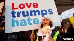 Seorang perempuan memegang papan bertuliskan "Love Trumps Hate" dan menyalakan lilin sebagai bagian dari aksi protes untuk menyuarakan Hak Perempuan "Lights for Rights" saat pelaksanaan pelantikan Trump sebagai Presiden ke-45 AS, 20 Januari 2017 di depan Theatre Royal de la Monnaie, Brussels, Belgia, 20 Januari 2017.