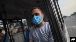 Un hombre usa una máscara contra la propagación de la enfermedad COVID-19, mientras viaja en un autobús a su casa en Managua, Nicaragua, el lunes 11 de mayo de 2020.