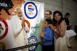 FILE - A group of attendees gesture in front of a poster of Indian Prime Minister Narendra Modi before a community reception at SAP Center in San Jose, California, Sept. 27, 2015.