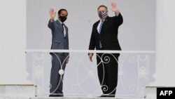This handout photograph taken and released on October 29, 2020 by the Indonesian Presidential Palace shows US Secretary of State Michael Pompeo (R) with Indonesian President Joko Widodo waving from the balcony of the Presidential Palace in Bogor.