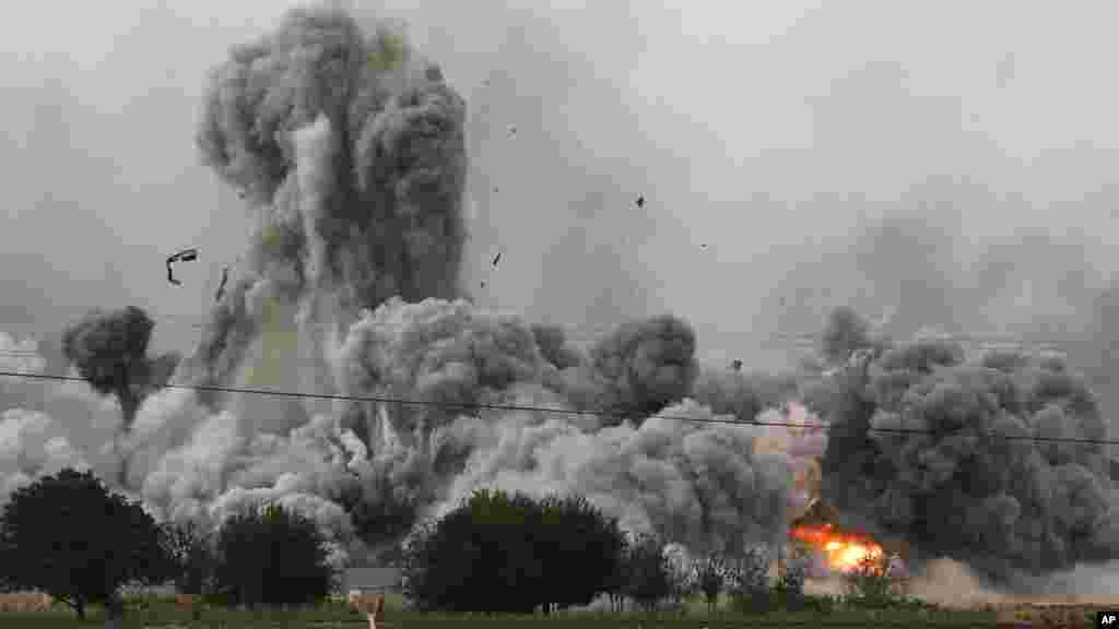 Une épaisse fumée, des débris et des flammes s&rsquo;élèvent après une frappe aérienne de la coalition menée par les Etats-Unis à Kobani, en Syrie alors que des combats s&rsquo;intensifient entre les Kurdes Syriens et des combattants de l&rsquo;Etat Islamique, comme observé depuis les faubourgs de Suruc, à la frontière Turco-Syrienne, dimanche le 12 octobre 2014. (AP Photo/Lefteris Pitarakis) 