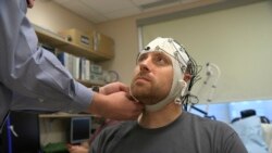 In this Nov. 20, 2019 image from video, Zach Ault is fitted with an EEG cap which uses electrodes to track the electrical activity of his brain, at the National Institutes of Health's hospital in Bethesda, Md. (AP Photo/Federica Narancio)