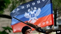 A pro-Russian gunman is seen behind barricades topped by a flag of the self-proclaimed Donetsk People's Republic, in Slovyansk, eastern Ukraine, May 8, 2014.