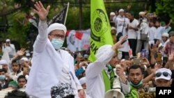 Rizieq Shihab (kiri), pemimpin Front Pembela Islam (FPI), menyapa para pendukungnya di markas FPI di Jakarta, setibanya dari Arab Saudi, 10 November 2020. (Foto oleh BAY ISMOYO/ AFP)