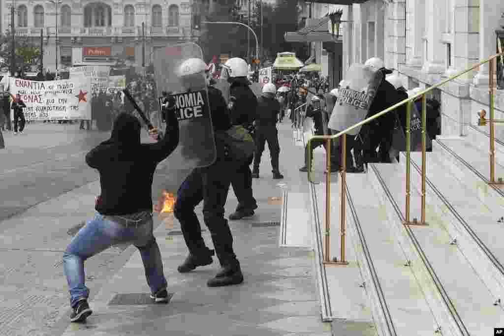 A protester uses a hammer to attack a riot police officer during clashes at a nationwide general strike in Athens, Greece. Workers walked off the job for an anti-austerity general strike that was disrupting public and private sector services across the country.