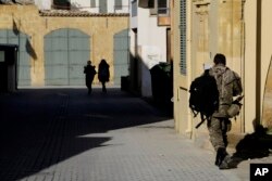 FILE - A Greek Cypriot soldier (R) walks towards a military guard post across the U.N. buffer zone that divides the Greek and Turkish Cypriots controlled areas, in the divided capital of Nicosia, Cyprus, Jan. 12, 2017.