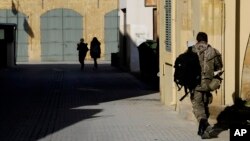 A Greek Cypriot soldier, right, walks toward a military guard post across the U.N. buffer zone that divides the Greek Cypriot- and Turkish Cypriot-controlled areas, in the divided capital Nicosia, Cyprus, Jan. 12, 2017. 