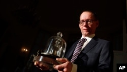 In this photo taken Wednesday, Oct. 17, 2018., the head of BIPM (International Bureau of Weights and Measures) Martin J.T. Milton holds a replica of the International Prototype Kilogram in Sevres, near Paris. (AP Photo/Christophe Ena)