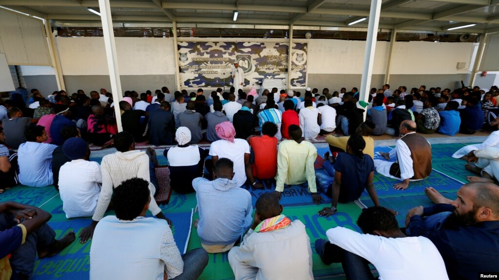 FILE - Migrants attend prayers at a detention center in Tripoli, Libya, June 15, 2018.