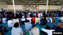 FILE - Migrants attend prayers at a detention center in Tripoli, Libya, June 15, 2018.