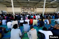 FILE - Migrants attend prayers at a detention center in Tripoli, Libya, June 15, 2018.
