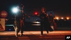 Arhiva - Marinac sprovodi službenicu Stejt dipartmenta koja nosi dete ka mestu za evakuaciju, na aerodromu u Kabulu, Avganistan, 15. avgusta 2021.