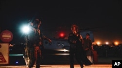 FILE - A Marine escorts a Department of State employee carrying a child to be processed for evacuation, at Hamid Karzai International Airport, in Kabul, Afghanistan, Aug. 15, 2021.