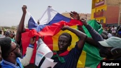 FILE - Protesters hold Russian and Senegalese flags during a Feb. 24, 2024, protest against the postponement of the presidential election scheduled for Feb. 25, in Dakar, Senegal. A commission on Feb. 27 recommended that the delayed election be held in early June.