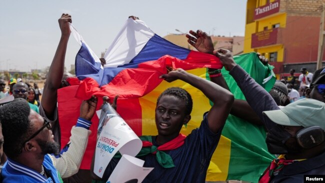 FILE - Protesters hold Russian and Senegalese flags during a Feb. 24, 2024, protest against the postponement of the presidential election scheduled for Feb. 25, in Dakar, Senegal. A commission on Feb. 27 recommended that the delayed election be held in early June.